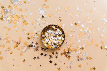 golden confetti in tin jar on beige background