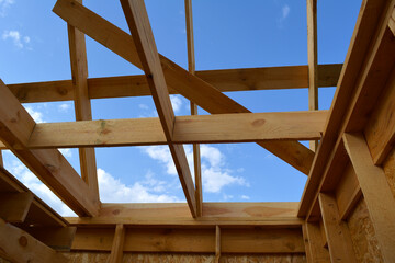 Construction of small wooden frame house. View from below on beams and roof rafters on the...
