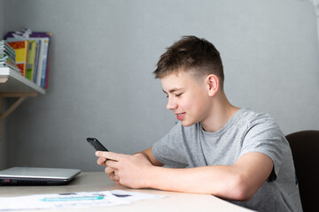 Fototapeta premium teenage boy using smartphone for study or communication, smiling and looking at screen