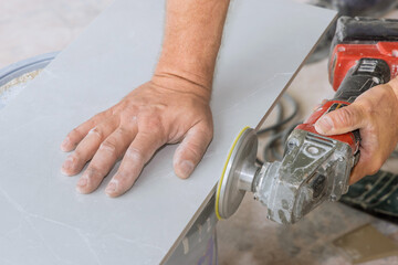 Worker using angle grinder polishing disk with diamond for polishing cut corner tiles with bathroom...