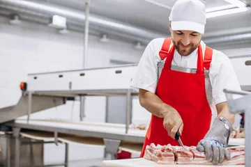 Fotobehang Man butcher at the freezer cutting meat © Petro