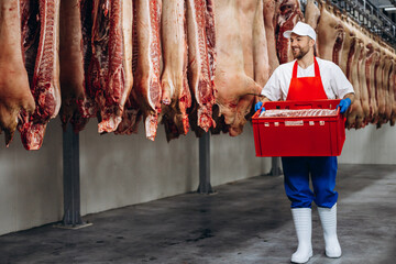 Buthcer at the freezer with box full of meat
