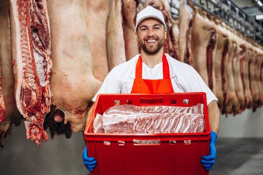 Buthcer at the freezer with box full of meat