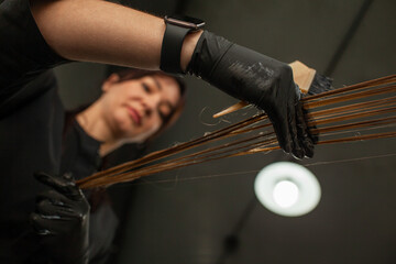 
Close-up of female hands holding the hair rows in professional hairstyles salon. The hairdresser...