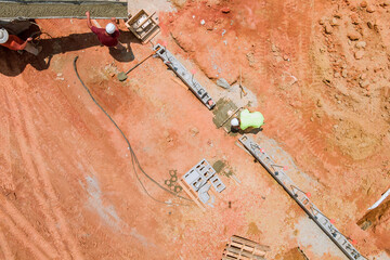 In an aerial top view, workers pour concrete columns on a construction site