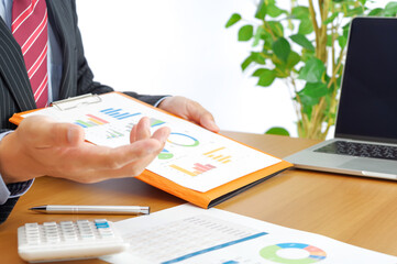 グラフ資料で説明をするスーツ姿の男性