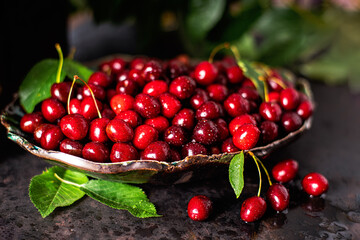 Fresh sweet Juicy tasty fruit.Fresh sweet cherry with green leaves on a dark background.Cherries in ceramic bowl. Fresh cherries in bowl on table.Cherries in earthenware and green leaves.