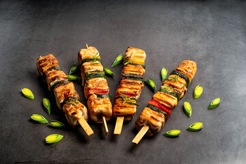 Top view.Grilled pieces of chicken meat on skewers.Grilled chicken kebab with vegetables on a black background.Chicken shish kebab with zucchini.