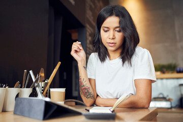 Unhappy female cafe manager calculating expenses standing behind the counter.