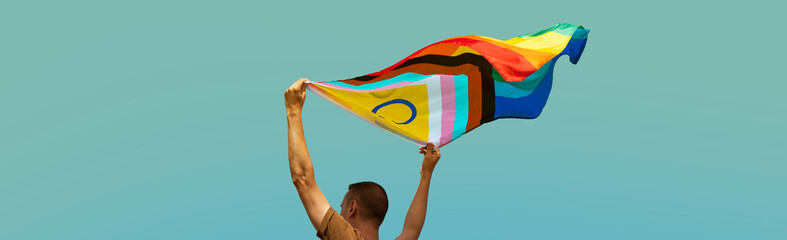 man waving a progress pride flag outdoors, banner