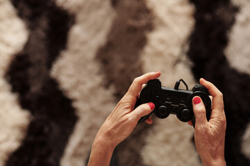 Hands of mature woman enjoying playing videogame at home