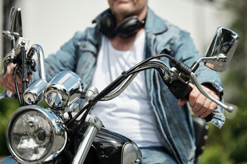 Fototapeta na wymiar Confident man in white t-shirt and demin jacket riding motorcycle