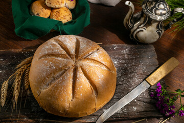 Natural homemade round country bread with smaller loaves with an old teapot decorated with ears of...