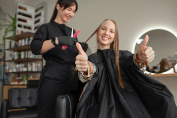 
Close-up of female hands holding the hair rows in professional hairstyles salon. The hairdresser paints or makes keratin to a girl in a professional salon