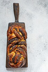 Freshly baked brioche/Babka with poppy seeds and chocolate on a wooden board. Braided dessert...