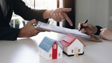 Real estate agent with house model hand putting signing contract,have a contract in place to...