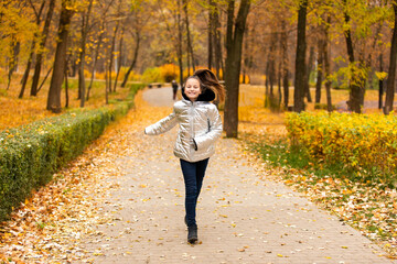 Beautiful smiling preteen girl running on path in autumn park
