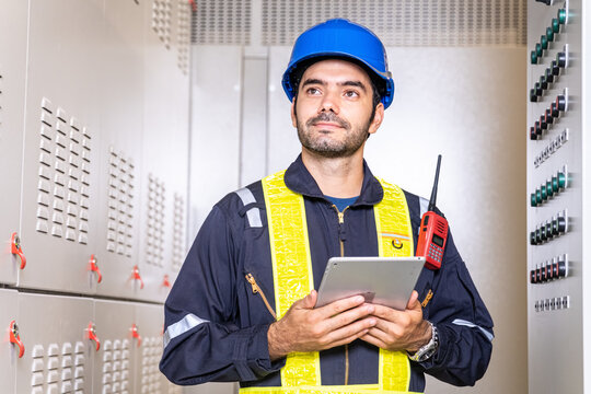 Maintenance engineer inspect relay protection system with laptop tablet computer. Electrician factory worker working with Bay control unit in container construction site. Medium voltage switchgear