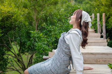 Fototapeta premium young woman in a cute dress sits relaxing in a garden walkway with many orange and green trees. The concept is refreshing, relaxed and freedom