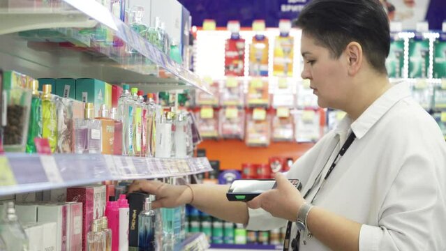 A female sales associate holding a barcode scanner device for lowering prices on merchandise