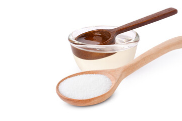 Sugar syrup in glass bowl and white sugar in wooden spoon isolated on white background.