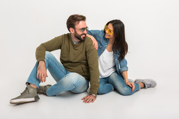 stylish couple sitting on floor in jeans