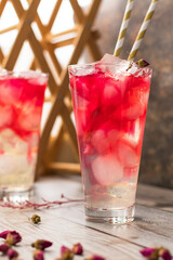 Homemade lemonade with rose syrup in glass tall glasses on the table. Cold refreshing drink with ice. Ovshala. vertical position.