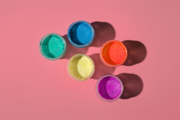 open jars with acrylic paint on a colored background, top view