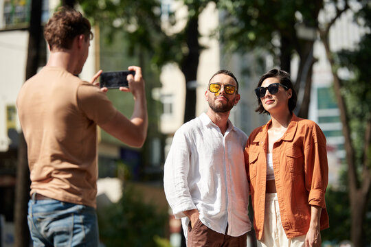 Friends in yellow sunglasses posing for photo on smartphone in park