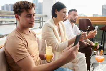 Young people spending time on social media instead of socializing at rooftop party