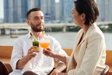 Smiling young man enjoying drinks and conversation with woman at rooftop bar