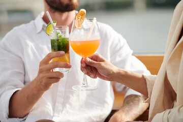 Cropped image of couple drinking fruit cocktails at outdoor party