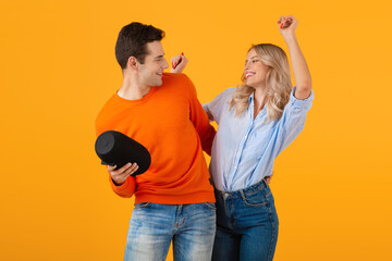 attractive stylish young couple holding wireless speaker