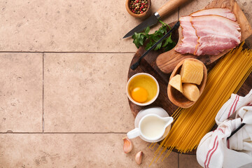 Ingredients for Pasta Carbonara. Traidtional Italian Pasta Carbonara Ingredients bacon, spaghetti, parmesan and egg yolk, garlic. Beige old tile table background. Top view. Copy space