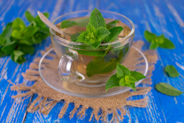 A cup of mint tea on a blue wooden background.Close-up.
