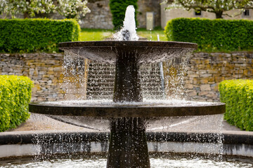 Old fountain in the renovated historic gardens of Dalheim monastery “Kloster Dalheim“ in Lichtenau near Paderborn Germany. Sprinkeling well with perfect symmetry on a sunny springtime day. - obrazy, fototapety, plakaty