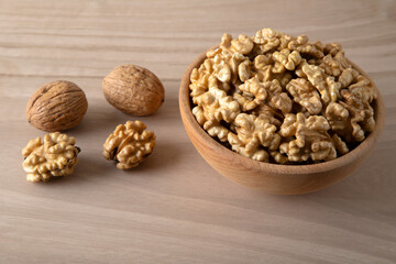 Bowl of walnuts and whole walnut kernels on wooden background,top view
