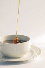 Honey being poured into a white pot, freshly produced