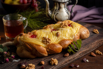 cake cake in the shape of a braid with pastry cream on top and nuts old teapot with cup of tea and glass bottle with milk for breakfast or snack