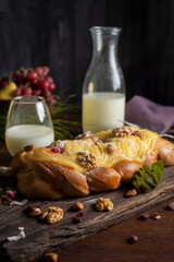cake cake in the shape of a braid with pastry cream on top and nuts old teapot with cup of tea and glass bottle with milk for breakfast or snack