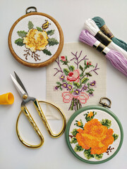 Vintage wooden embroidery hoops, scissors, needle, thread and fabric with floral cross-stitch...
