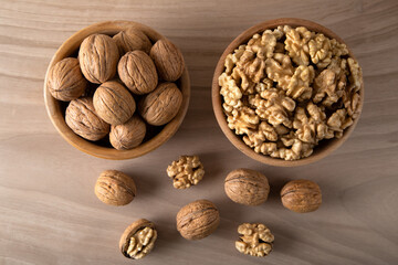 Bowl of walnuts and whole walnut kernels on wooden background,top view
