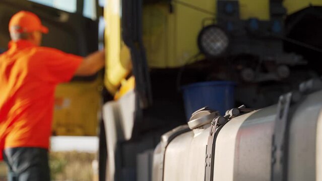 Truck driver refuels a fuel tank with diesel filling gun intruck at petrol station. Concept of increasing soaring fuel prices, economical problems. Trucker man refilling the motor lorry.
