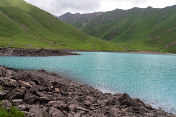 Landscape of an alpine lake with blue water and high green mountains