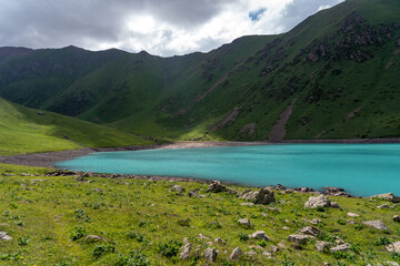 Landscape of an alpine lake with blue water and high green mountains