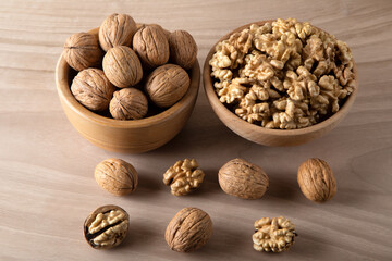 Bowl of walnuts and whole walnut kernels on wooden background,top view
