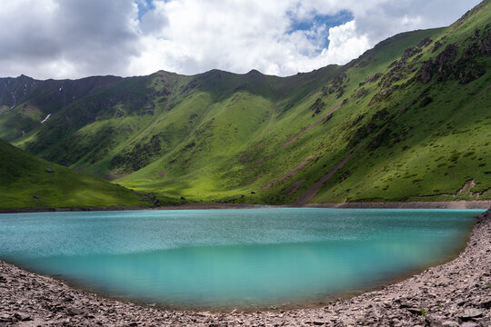 Landscape of an alpine lake with blue water and high green mountains