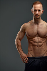 Young male athlete posing. Handsome athletic male power guy. Fitness muscular person. Young athlete showing muscles in the studio, posing shirtless on gray background.