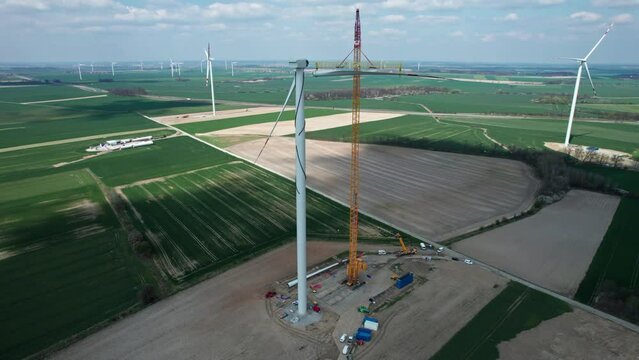 Constructing a wind farm, a crane lifts a windmill blade.