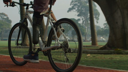 Fototapeta premium Athletic disabled man with prosthetic leg riding bicycle outside